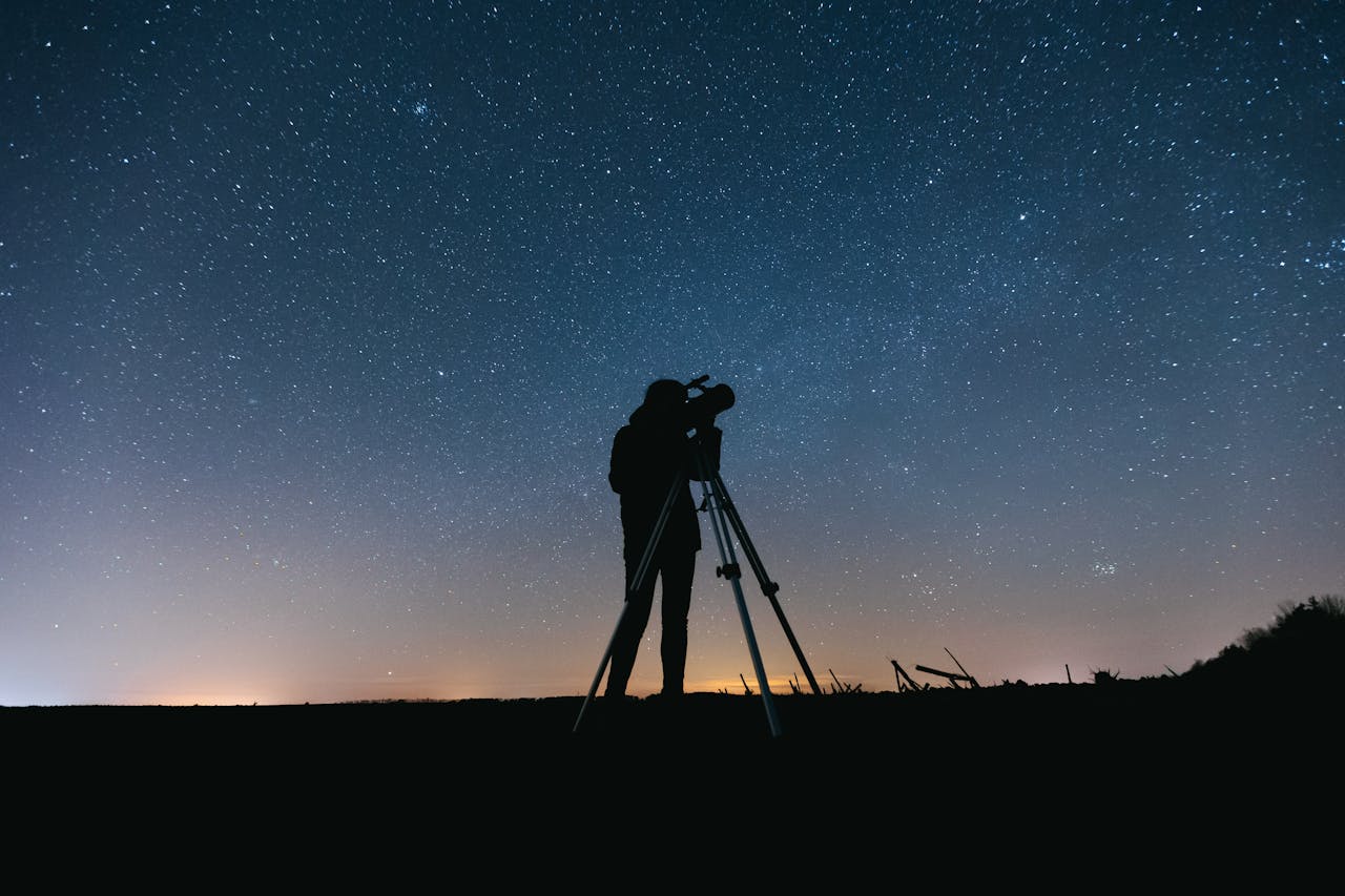 person looking at the stars using a telescope